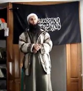 Imam Bilal Bosnic vor der Schwarzen Fahne des Kalifats