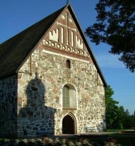 Die Sibbo-Kirche mit gotischen Ziegel-Verzierungen an der Frontseite, auf die der um 1800 erbaute Glockenturm seinen Schatten wirft.